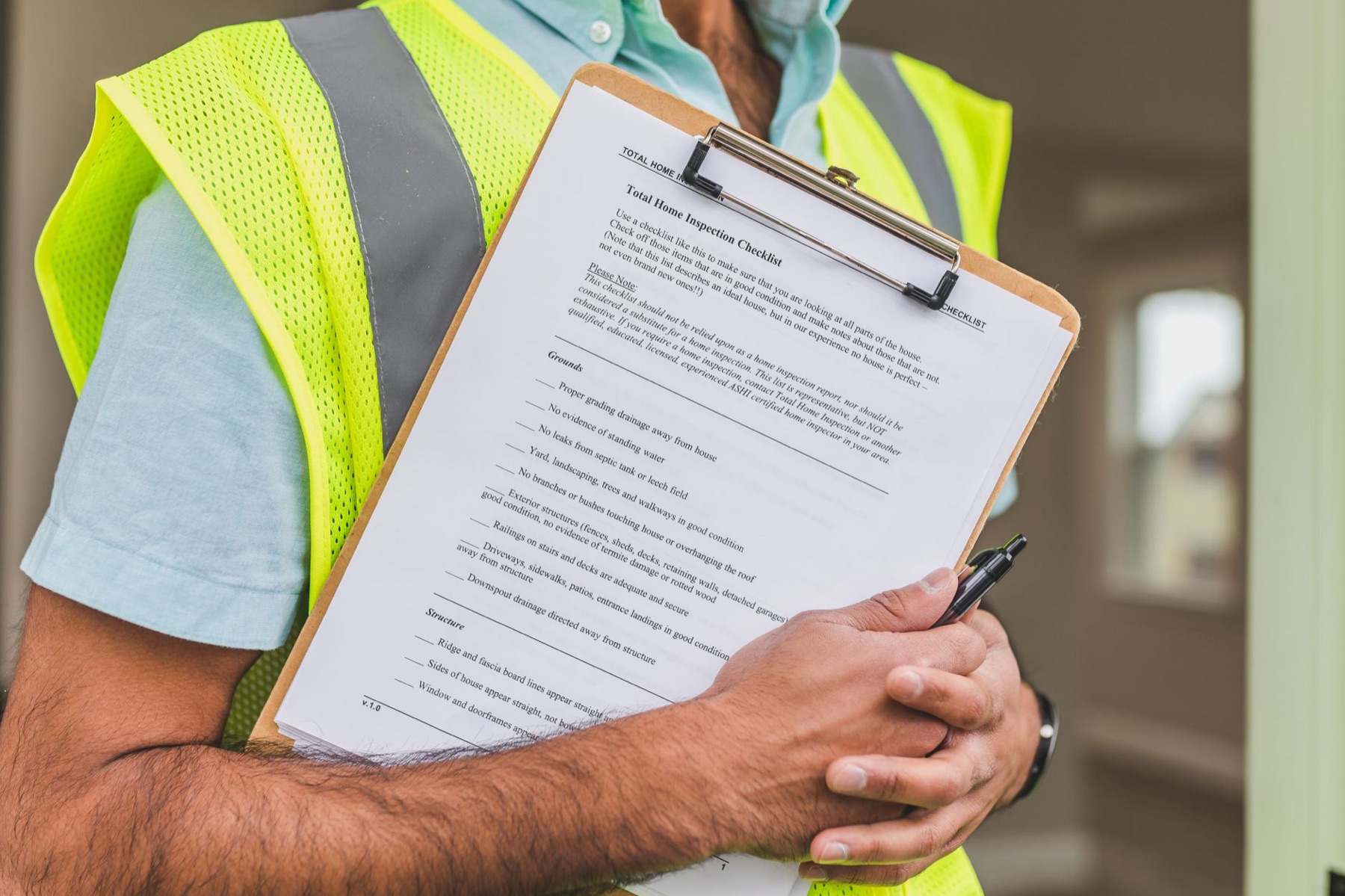 diagnostiqueur en gilet haute visibilité tenant une checklist d'inspection immobilière sur un écritoire