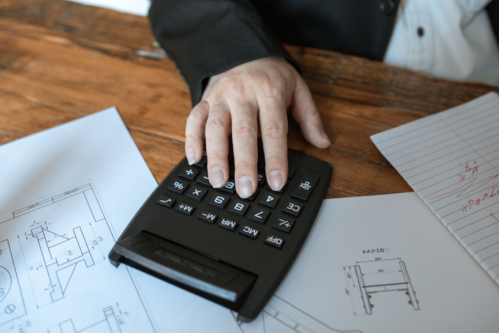 documents de devis de travaux, plan et calculatrice posés sur un plan de travail