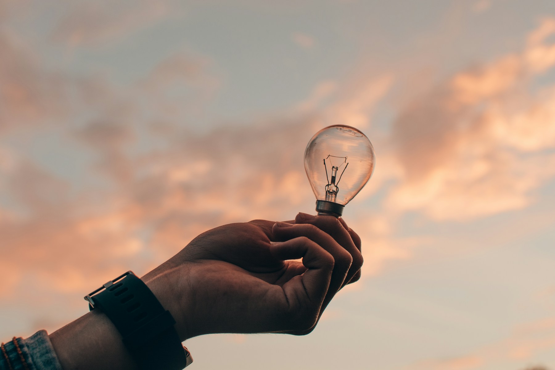 Ampoule LED basse consommation tenue en main, symbole des gestes simples pour réduire sa facture
