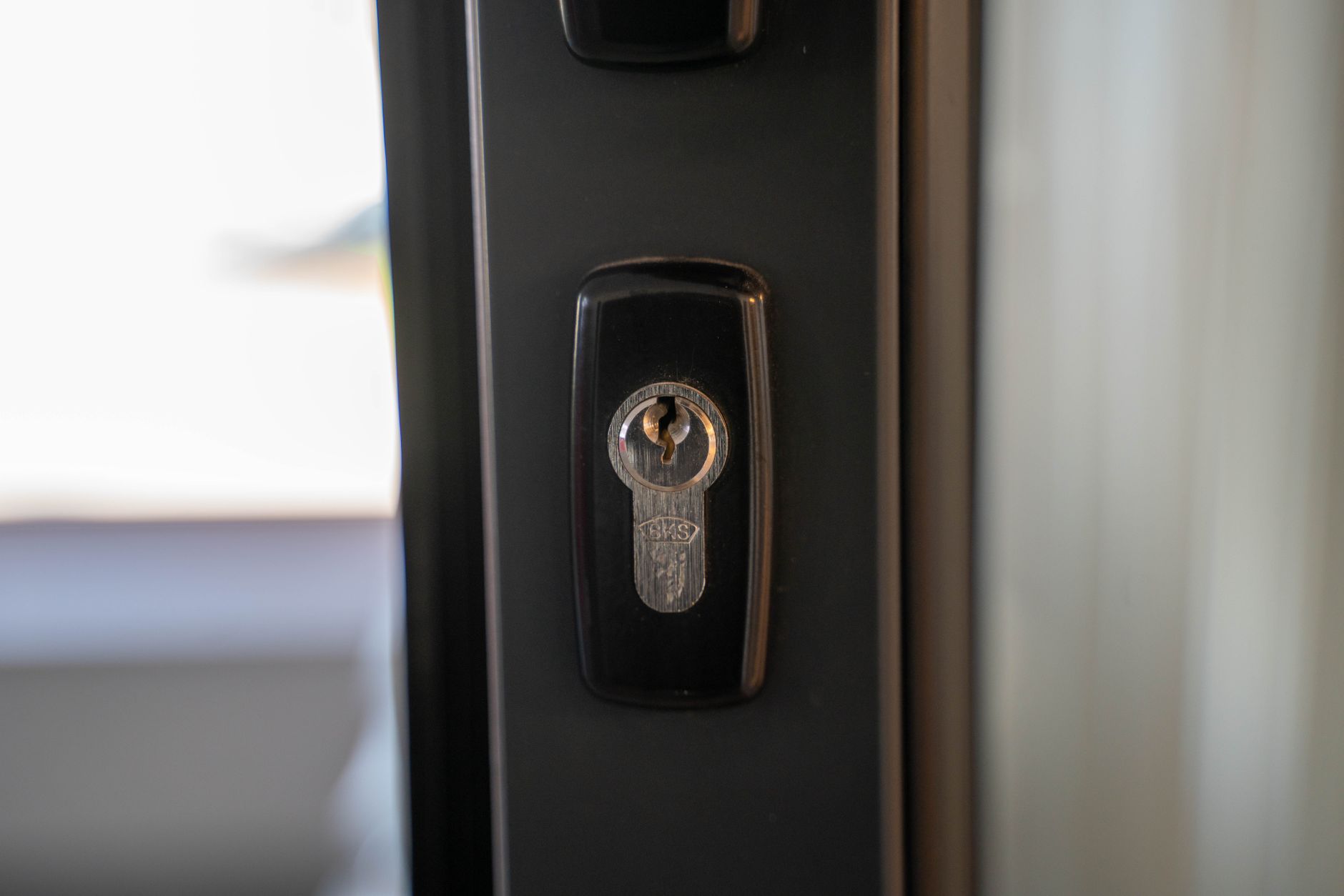 gros plan sur une serrure de porte d'entrée et son barillet, clé insérée
