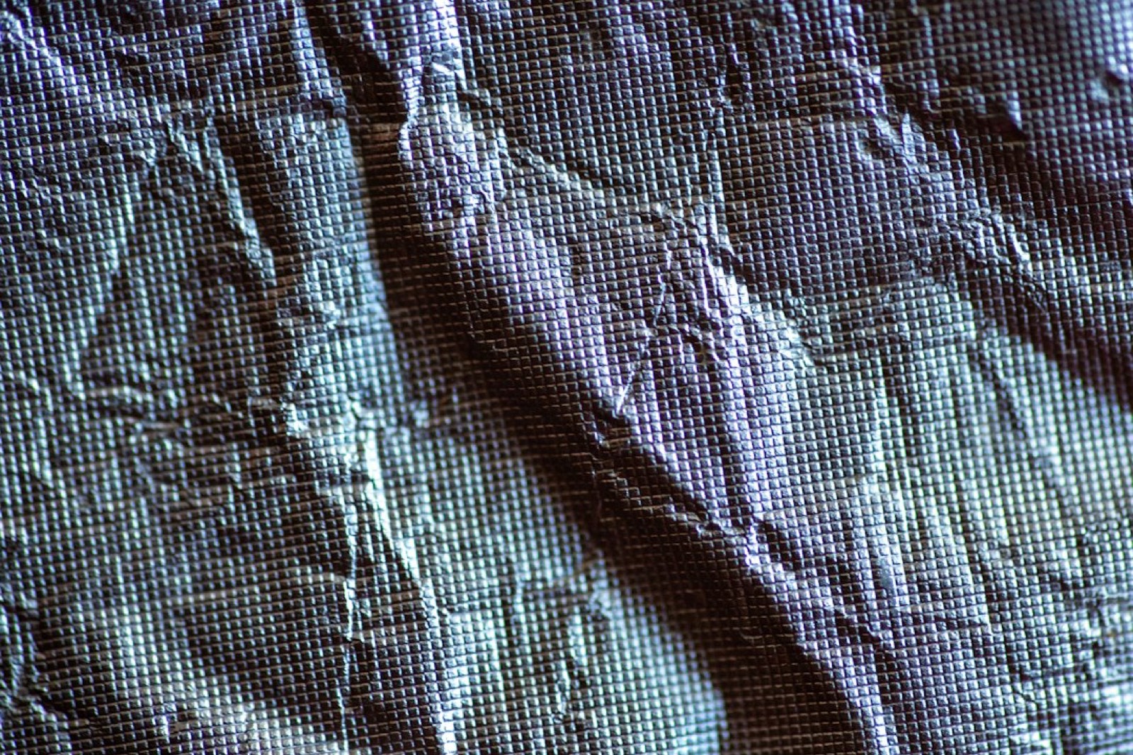 Gros plan sur une toile maillée et ses œillets métalliques de fixation