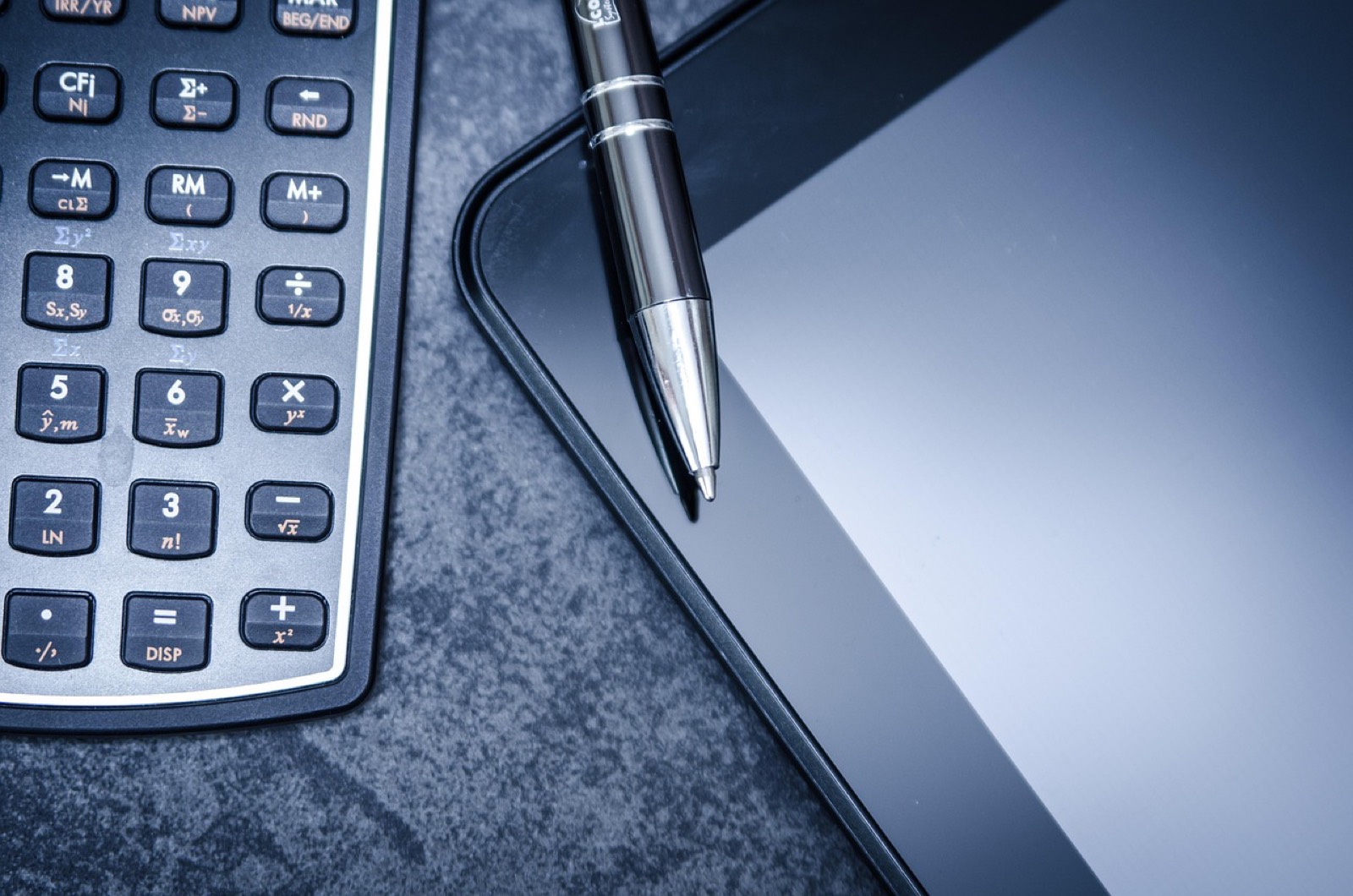 Calculatrice, stylo et documents chiffrés posés sur un bureau pour vérifier le total et la TVA d'un devis